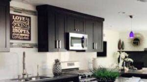 Moderni keittiö, jossa integroitu mikroaaltouuni mustien kaapistojen keskellä