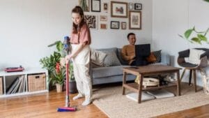 Nainen käyttää parasta varsi-imuria modernissa olohuoneessa, siivoten mattoa tehokkaan akkuimurin avulla
